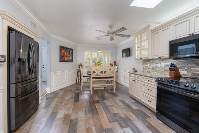 kitchen featuring stainless steel appliances, wood finished floors, cream cabinetry, light stone countertops, and glass insert cabinets