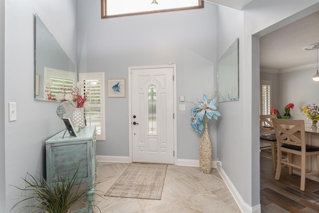 foyer with ornamental molding and baseboards