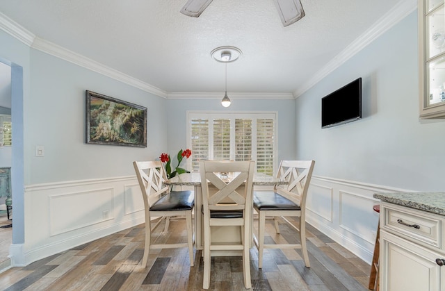 dining room with crown molding, a textured ceiling, and wood finished floors