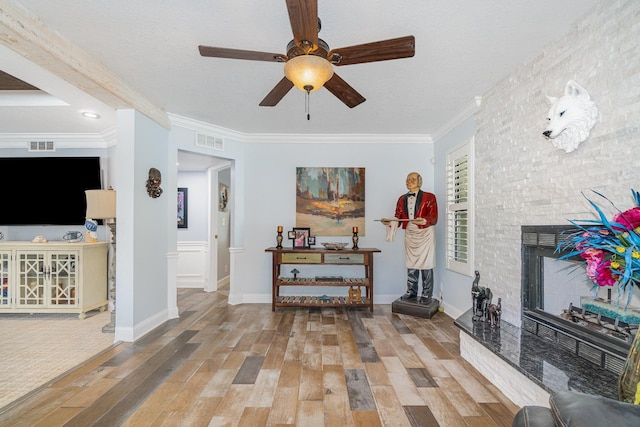 living area with crown molding, visible vents, and wood finished floors