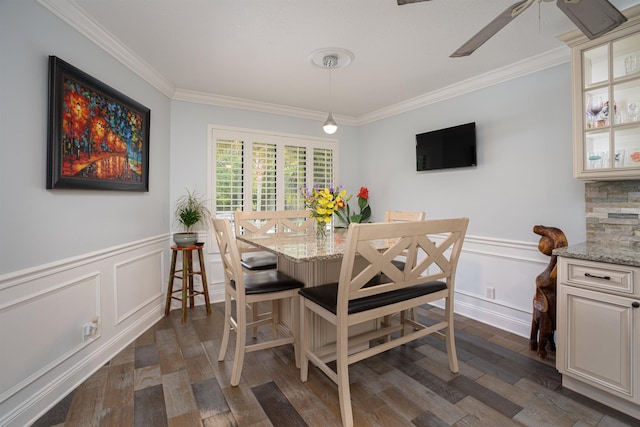 dining room with a wainscoted wall, ceiling fan, dark wood finished floors, and crown molding