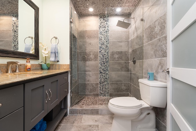 bathroom with a stall shower, tile walls, vanity, and toilet