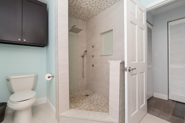 bathroom featuring walk in shower, toilet, and baseboards