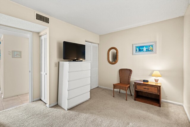 sitting room featuring visible vents, baseboards, light colored carpet, and light tile patterned flooring