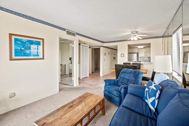 living area featuring light carpet, visible vents, a textured ceiling, and ceiling fan