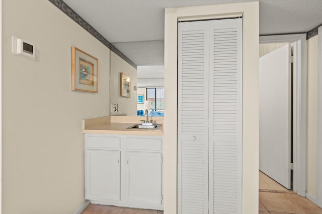 bathroom with vanity, a closet, tile patterned flooring, and a textured ceiling