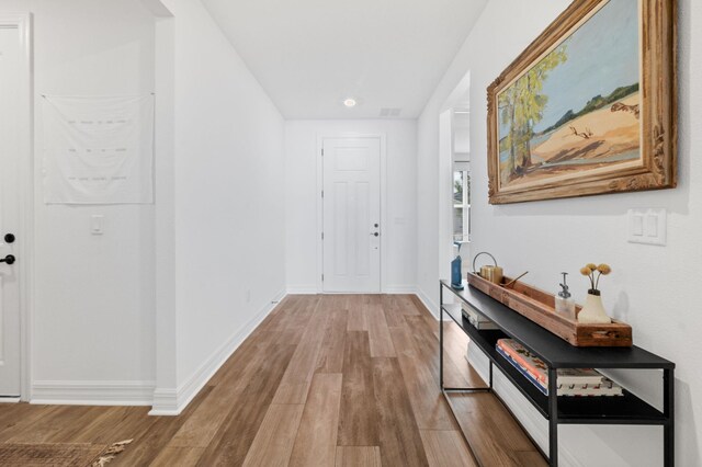 corridor featuring wood finished floors, baseboards, and recessed lighting