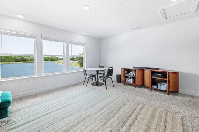 carpeted office space featuring a water view, baseboards, recessed lighting, and a textured ceiling