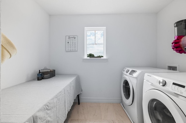 washroom with washing machine and clothes dryer, light marble finish floors, and baseboards