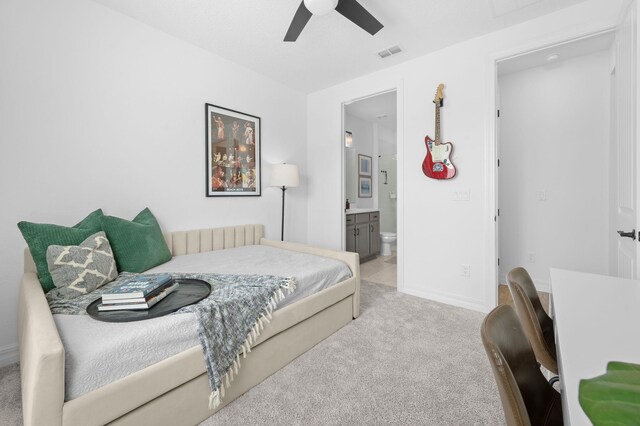 bedroom featuring light carpet, connected bathroom, a ceiling fan, and baseboards