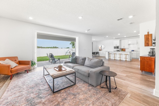 living area featuring light wood finished floors, recessed lighting, and a textured ceiling