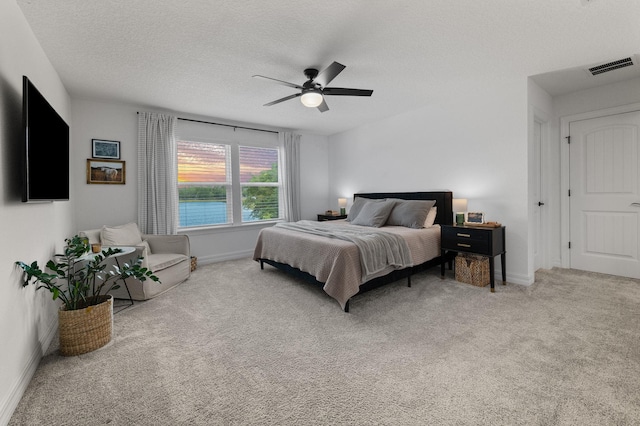 carpeted bedroom with baseboards, ceiling fan, and a textured ceiling