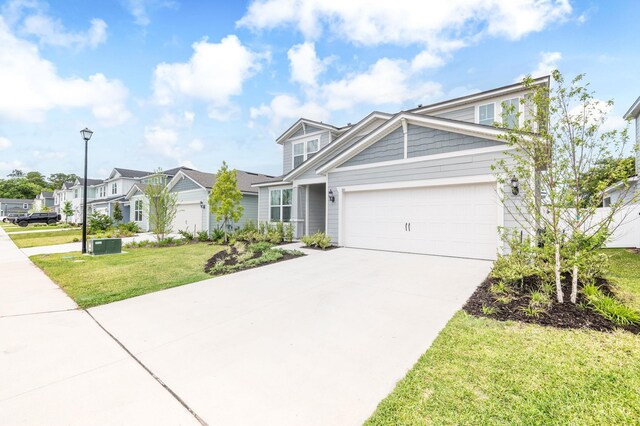 view of front of house with an attached garage, driveway, a front yard, and a residential view