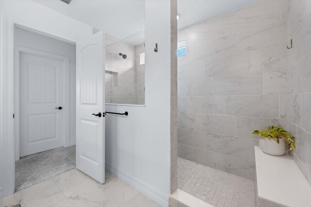 full bathroom featuring walk in shower, marble look tiles, and baseboards