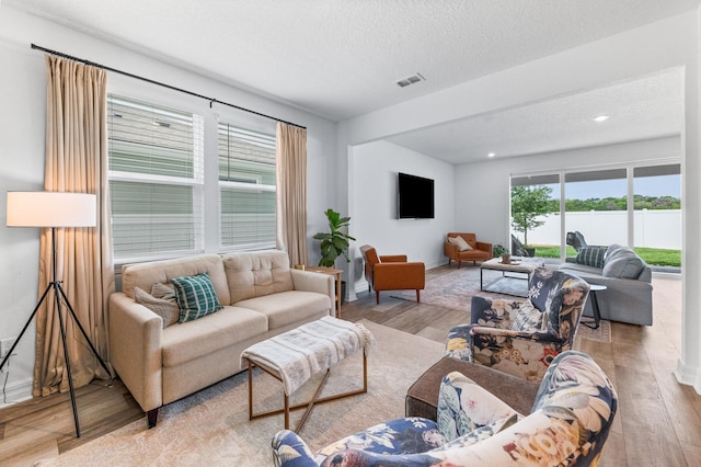 living room featuring wood finished floors, a textured ceiling, baseboards, and recessed lighting