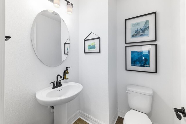 half bath featuring toilet, baseboards, and wood finished floors