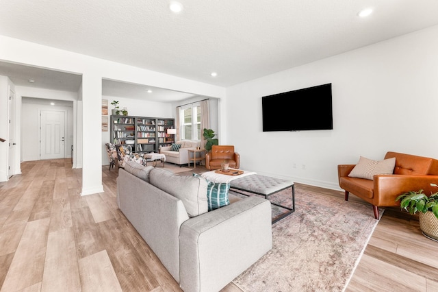 living room featuring light wood finished floors, recessed lighting, and baseboards