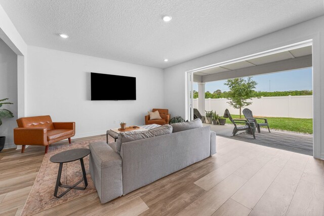 living room with light wood-style flooring, a textured ceiling, and recessed lighting