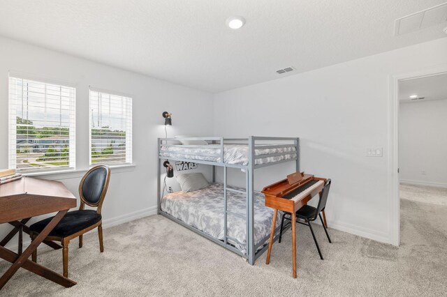 carpeted bedroom featuring baseboards and an office area