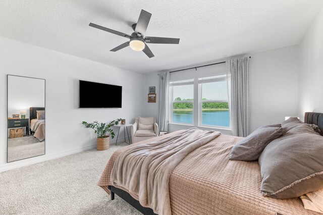 carpeted bedroom with ceiling fan and a textured ceiling