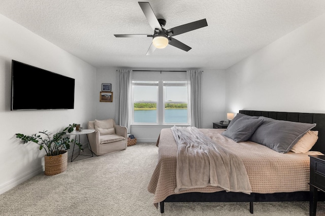 carpeted bedroom featuring a textured ceiling, baseboards, a ceiling fan, and a water view