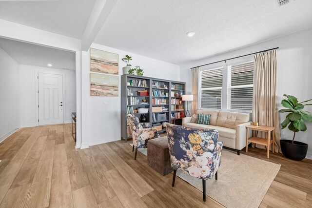sitting room with light wood-style flooring, recessed lighting, baseboards, and a textured ceiling