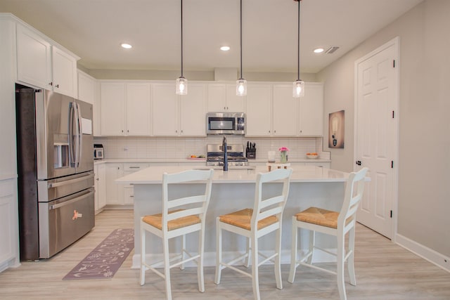 24 Pepperpike Way, Saint Augustine, FL 32092 - kitchen with stainless steel appliances, light wood finished floors, light countertops, backsplash, and white cabinetry