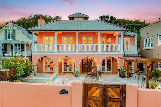 back house at dusk featuring french doors, a balcony, and ceiling fan