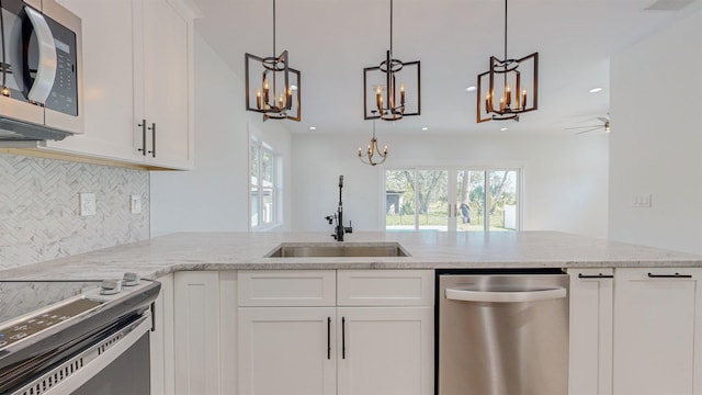 24 E Park Ave, Saint Augustine, FL 32084 - kitchen featuring appliances with stainless steel finishes, a chandelier, decorative backsplash, light stone countertops, and recessed lighting