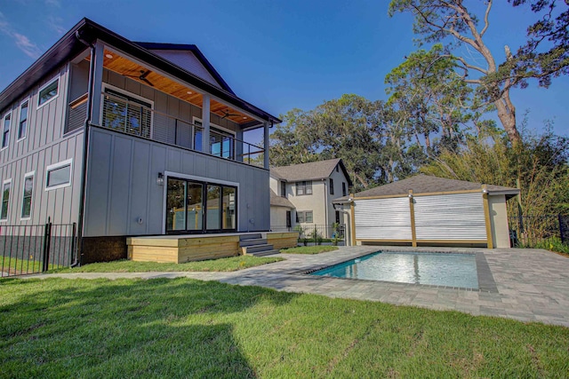 back of property featuring a yard, a balcony, an outdoor structure, and a garage