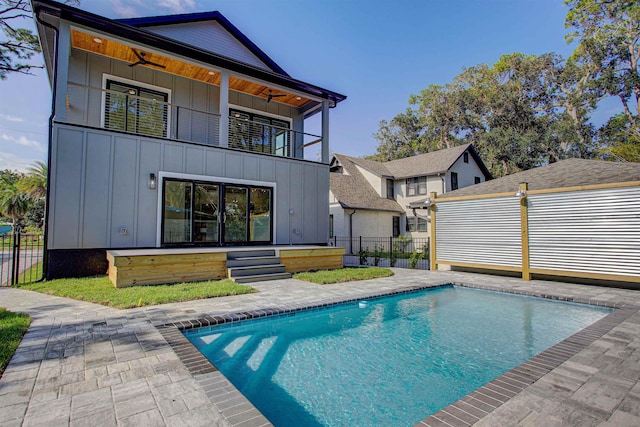 back of property with a balcony, a patio area, and a fenced in pool