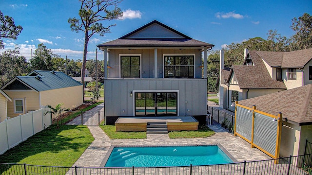 rear view of property with a fenced in pool, a patio area, and a yard