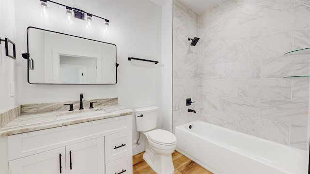 full bathroom featuring hardwood / wood-style floors, vanity, tiled shower / bath combo, and toilet