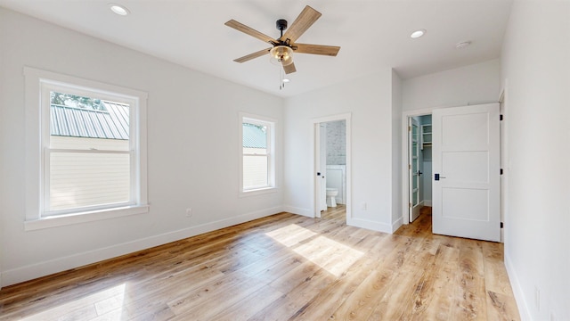 unfurnished bedroom with connected bathroom, light hardwood / wood-style flooring, a spacious closet, and multiple windows