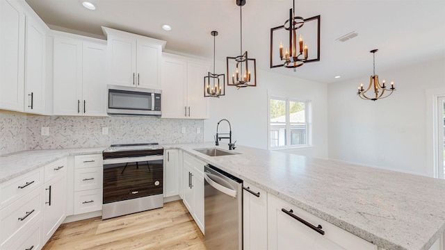 kitchen with pendant lighting, white cabinets, sink, light hardwood / wood-style floors, and stainless steel appliances