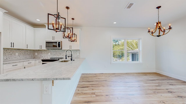 kitchen featuring pendant lighting, light hardwood / wood-style floors, white cabinets, and sink