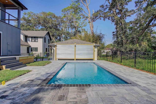 view of pool with a patio area, an outdoor structure, and a garage