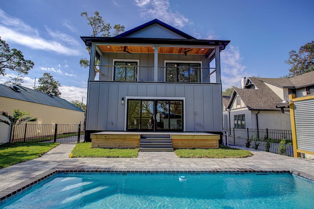 back of property with a fenced in pool, a patio area, ceiling fan, and a balcony