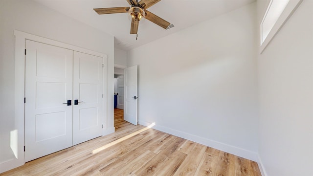 unfurnished bedroom featuring ceiling fan, light wood-type flooring, and a closet