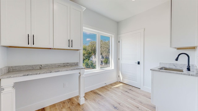 kitchen featuring light stone countertops, sink, white cabinets, and light hardwood / wood-style floors