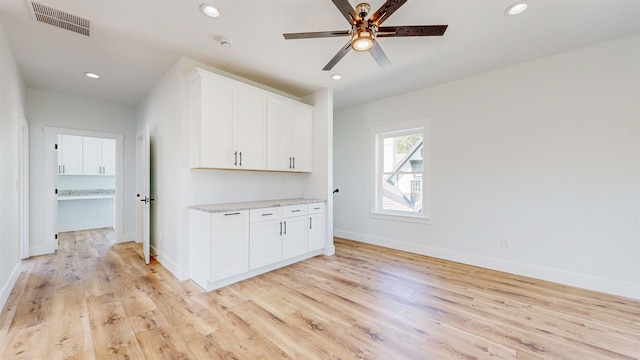 interior space with ceiling fan, light hardwood / wood-style flooring, and white cabinets