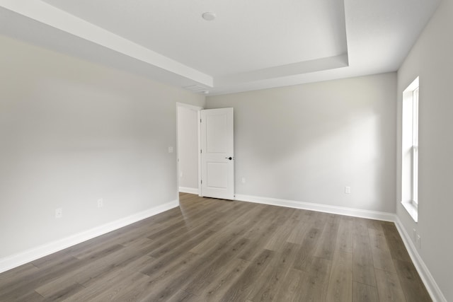 empty room with dark hardwood / wood-style floors and a tray ceiling