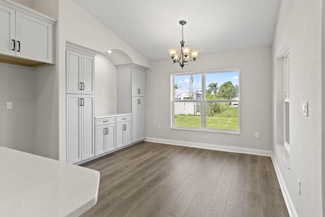 unfurnished dining area featuring dark wood-type flooring and a chandelier