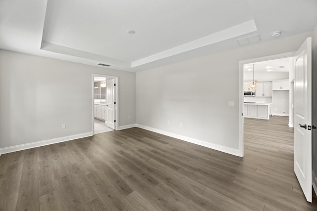 empty room featuring a raised ceiling and dark wood-type flooring