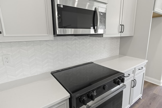 kitchen with electric range oven, white cabinetry, dark hardwood / wood-style flooring, and tasteful backsplash