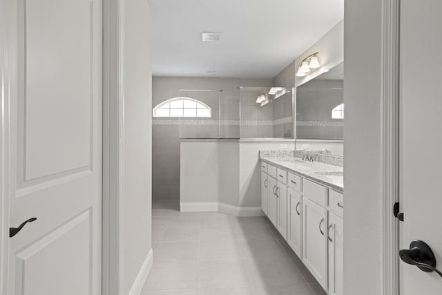 bathroom featuring vanity, tile patterned flooring, and a tile shower