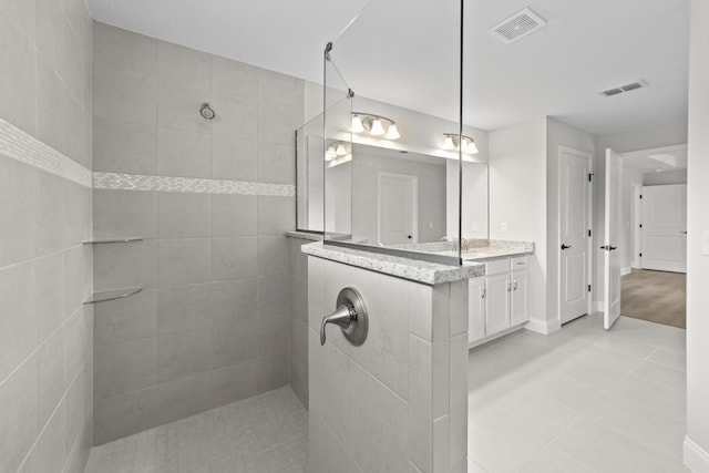 bathroom featuring tile patterned floors, tiled shower, and vanity