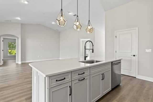 kitchen with a kitchen island with sink, hanging light fixtures, vaulted ceiling, stainless steel dishwasher, and sink