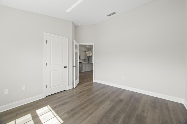 spare room featuring dark hardwood / wood-style floors and a notable chandelier