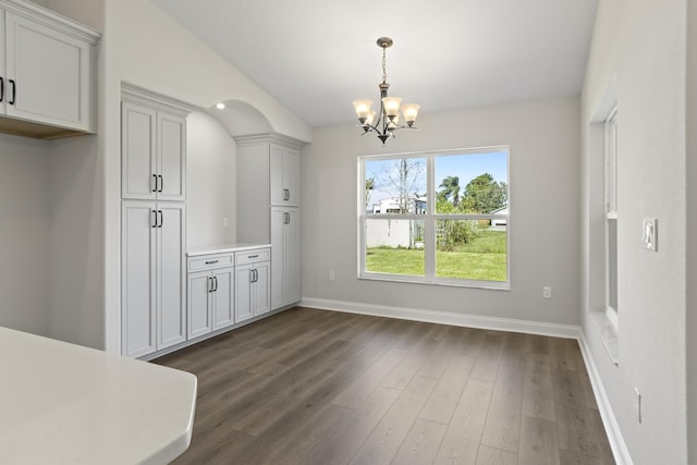 unfurnished dining area with dark wood-type flooring and a notable chandelier